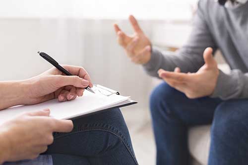 hands of doctor taking notes and patient gesturing