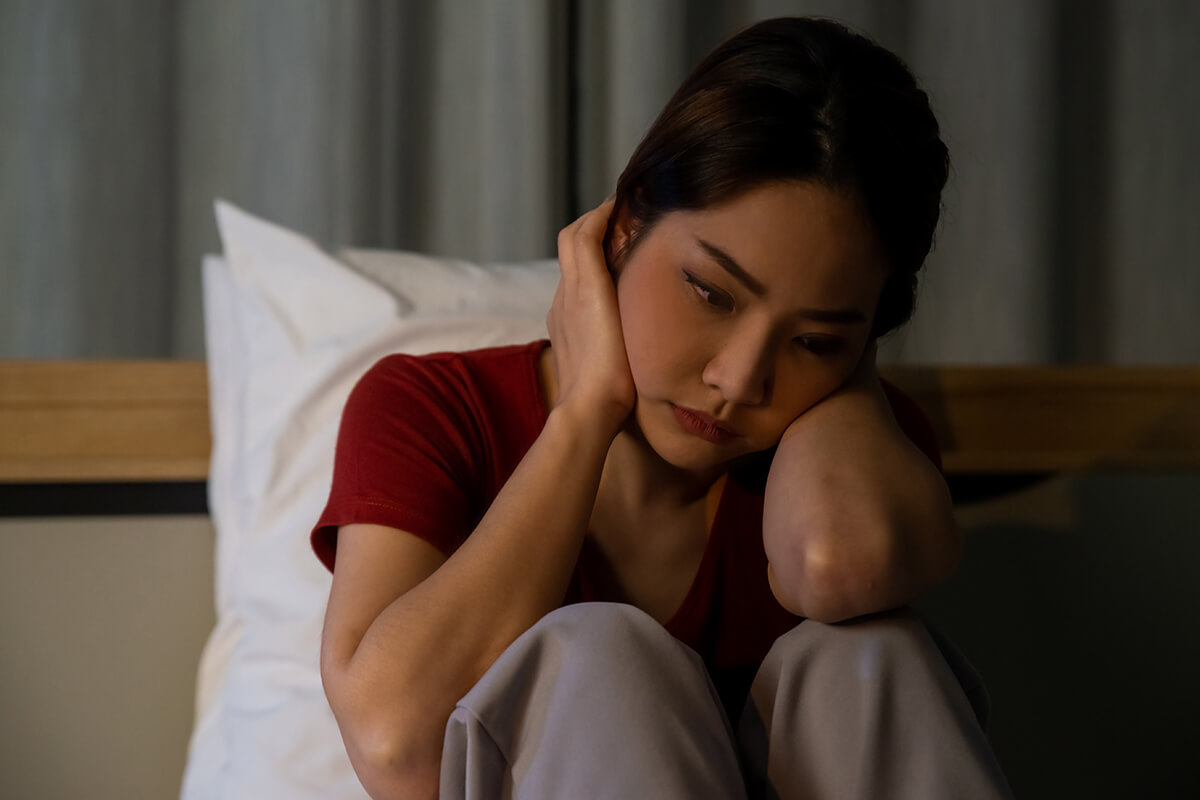 alcohol withdrawal symptoms woman in dark on bed dealing with alcohol withdrawal symptoms