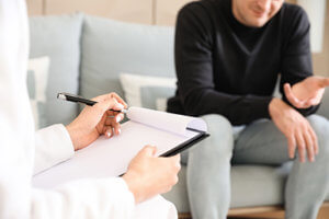 therapist taking notes from patient in prescription drug addiction treatment program