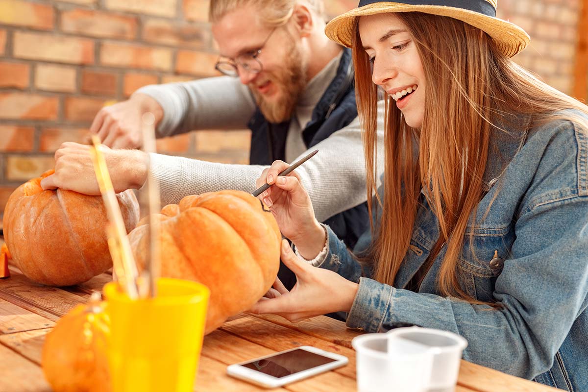 couple enjoying a sober halloween by painting pumpkins