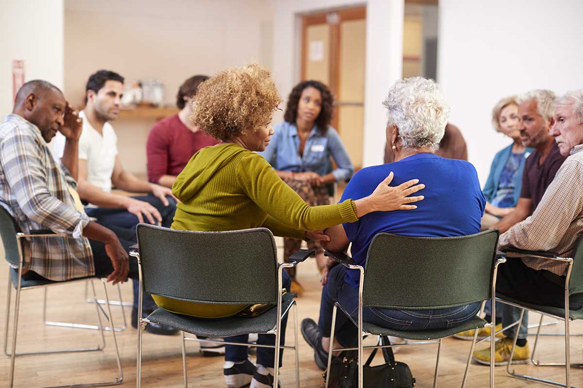 People Attending Self Help Therapy Group Meeting In Community Center woman discusses the how important group therapy is