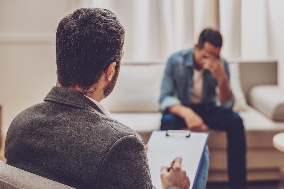 an upset man talking to his doctor about a partial hospitalization program