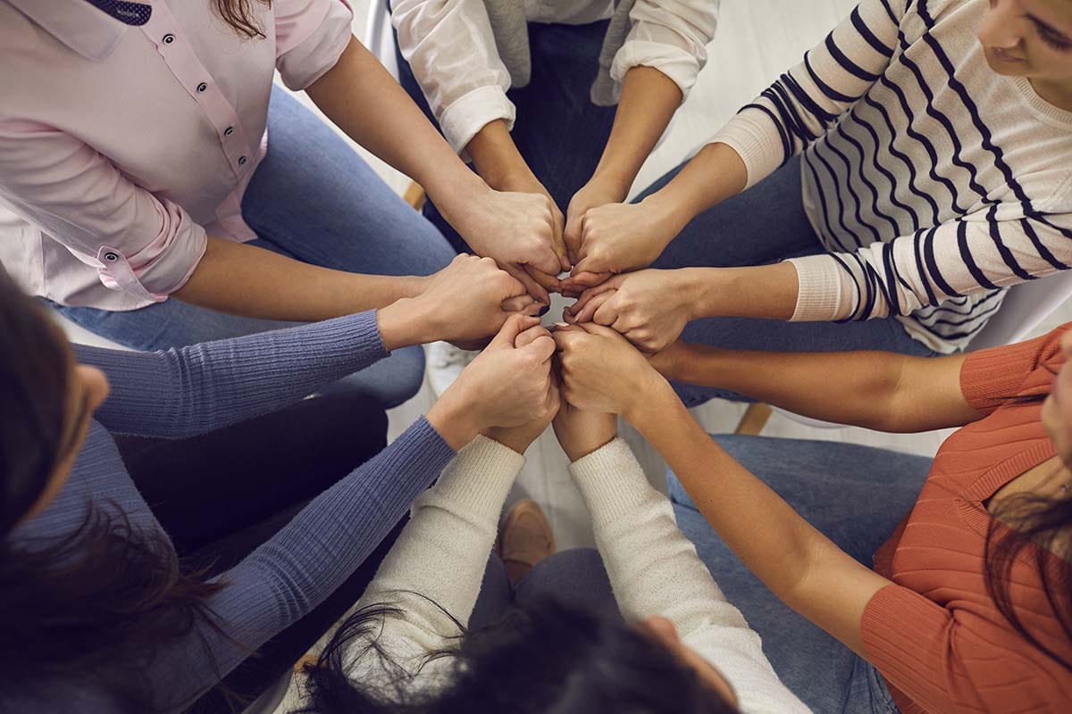 a group of people holding hands at an outpatient treatment program