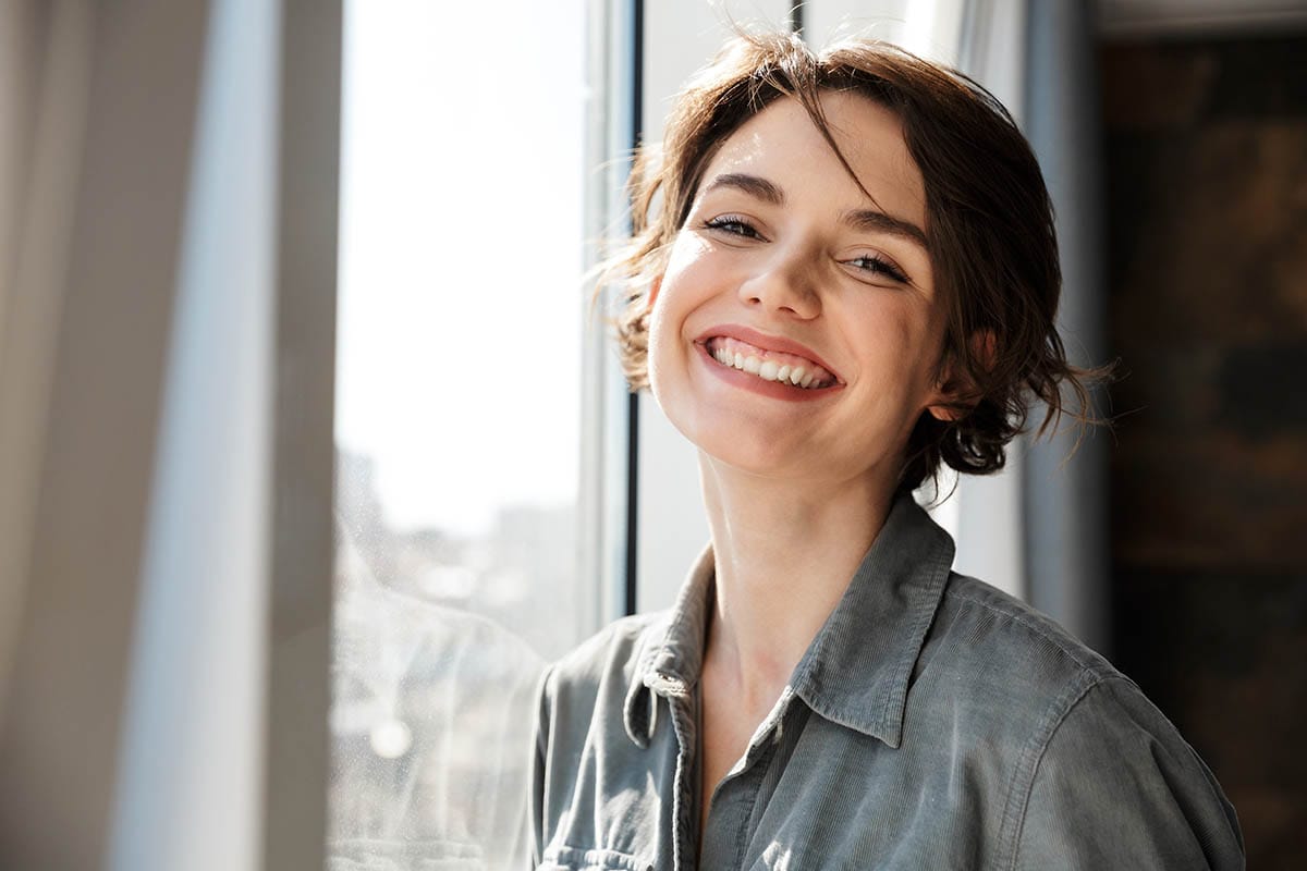 a woman smiling by her window happy about outpatient treatment programs