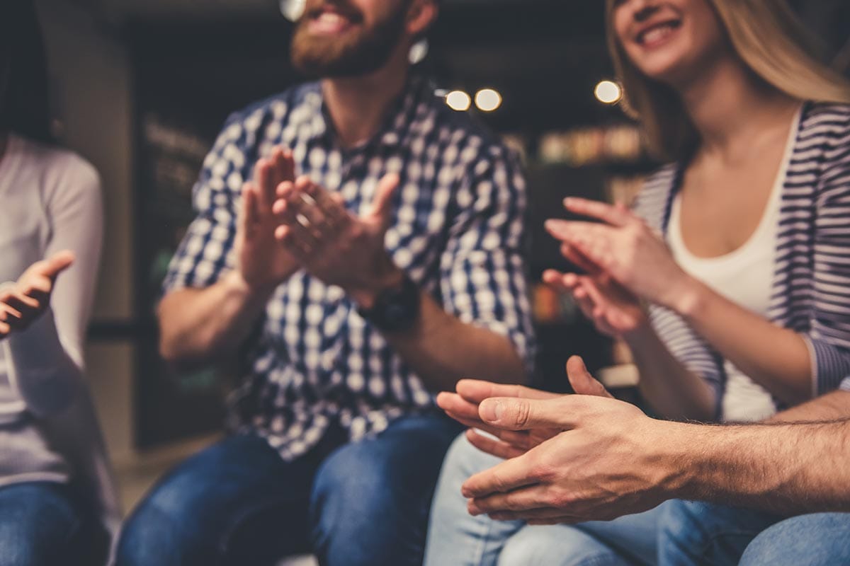 a group of people clapping at an addiction recovery center